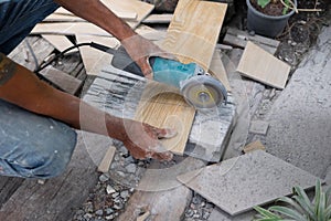 Worker using a hand circular saw to cut a tile