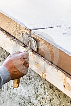 Worker Using Hand Groover On Wet Cement Forming Coping Around New Pool