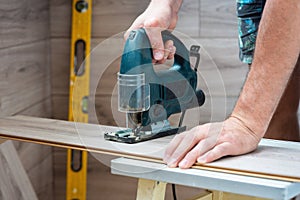 A worker using a jigsaw saws laminate boards