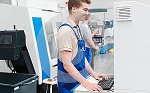 Worker using keyboard to enter data into a machine on factory floor