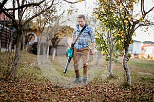 Man, Worker using leaf blower, garden vacuum and cleaning up the garden