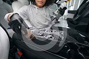 Worker using leather cleaner and brush for cleaning car upholstery