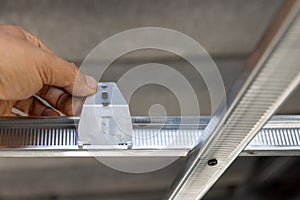 Worker is using locking keys to lock top cross rails to furring channels in concealed ceiling