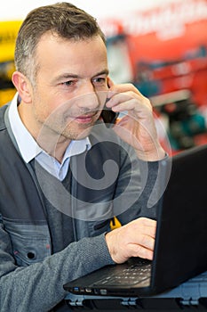worker using phone and laptop in store