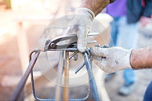 Worker using pincers and steel wire to secure bars for concrete pouring