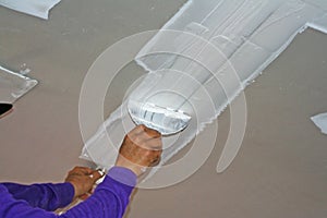 Worker using plaster gypsum on putty knife at ceiling