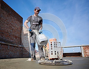 Worker using power trowel machine at construction site.