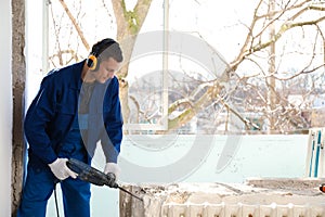 Worker using rotary drill hammer for window installation