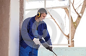 Worker using rotary drill hammer for window installation