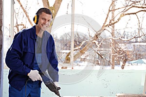 Worker using rotary drill hammer for window installation