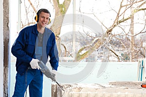 Worker using rotary drill hammer for window installation