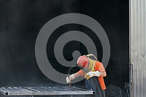 Worker using sandblaster for cleaning surface of metal