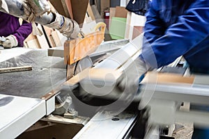 Worker using saw machine to make furniture at carpenterâ€™s work