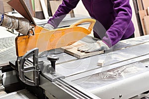 Worker using saw machine to make furniture at carpenterâ€™s work