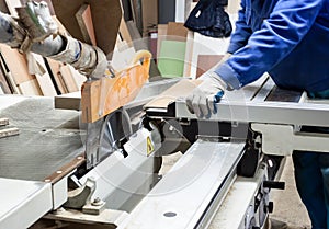 Worker using saw machine to make furniture at carpenterâ€™s work