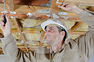 worker using screwdriver on wooden beam