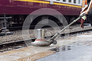 Worker using scrubber machine for cleaning and polishing floor. Cleaning maintenance train at railway station