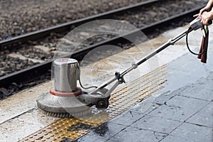 Worker using scrubber machine for cleaning and polishing floor. Cleaning maintenance train at railway station