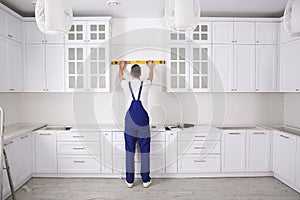 Worker using spirit level while installing new furniture in kitchen