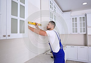 Worker using spirit level while installing furniture in kitchen