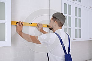 Worker using spirit level while installing furniture in kitchen