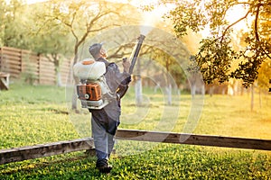 worker using sprayer for organic pesticide distribution in fruit orchard