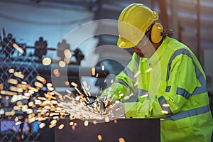 A worker is using a steel grinder in the factory. Industrial Worker Using Angle Grinder and Cutting a Metal Tube. Worker in Safety