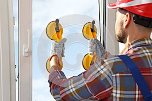 Worker using suction lifters during plastic window installation