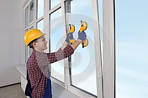 Worker using suction lifters during plastic window installation