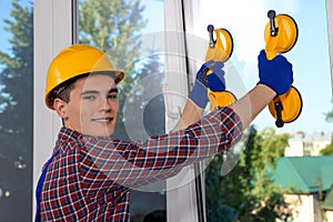 Worker using suction lifters during plastic window installation indoors photo