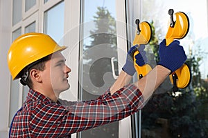 Worker using suction lifters during plastic window installation indoors photo