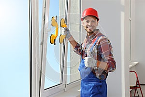 Worker using suction lifters during plastic window installation indoors photo