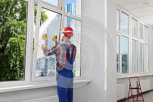 Worker using suction lifters during plastic window installation indoors photo