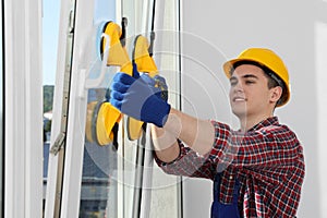 Worker using suction lifters during plastic window installation indoors photo