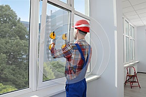 Worker using suction lifters during plastic window installation indoors photo