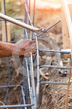 Worker Using Tools To Bend Steel Rebar At Construction Site