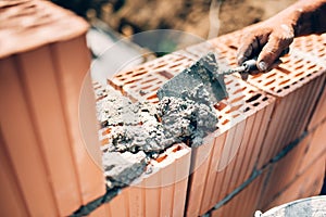 Worker using trowel and tools for building exterior walls with bricks and mortar