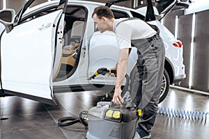 Worker with vacuum cleaner, car dry cleaning