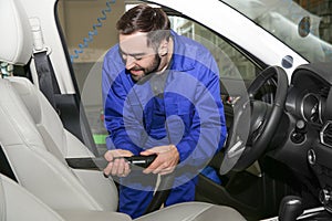 Worker vacuuming automobile seat. Car wash service