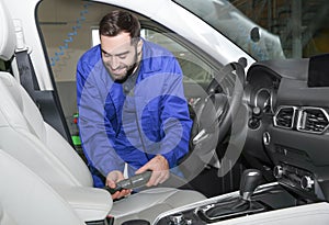 Worker vacuuming automobile seat, view from inside