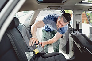 worker vacuuming and cleaning automobile. Car care and detailing concept