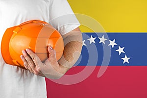 Worker with Venezuela flag on background for working on labor day. Construction concept