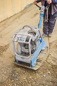 Worker with vibrating plate compactor machine