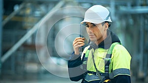 Worker with walkie talkie and safety equipment on oil plant