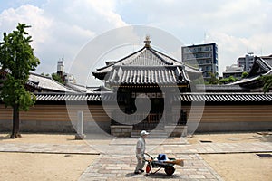 A worker walking in front of Japanese shrine`s gate