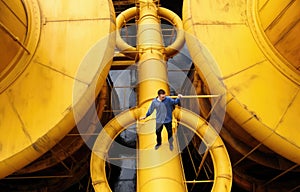 A worker walks on a ladder under a large pipe on an oil rig in the middle of the sea