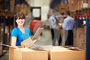 Worker In Warehouse Checking Boxes Using Digital Tablet