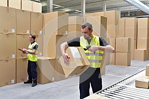 Worker in a warehouse in the logistics sector processing packages on the assembly line - transport and processing of orders in