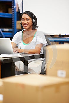 Worker In Warehouse Wearing Headset And Using Laptop