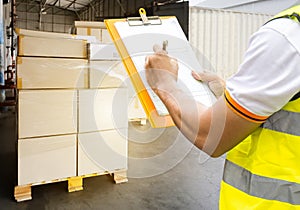 Worker warker holding clipboard checking control load shipment goods into cargo truck.